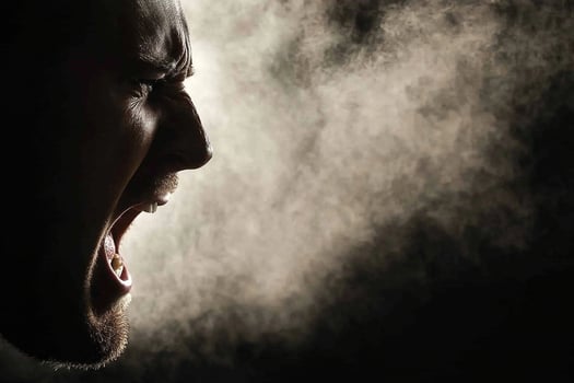 A man is screaming in the dark with smoke coming out of his mouth photo