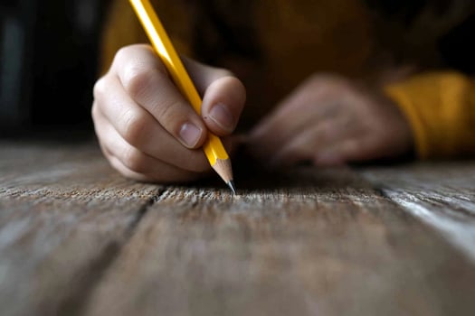 A person holding a pencil on a wooden table photo