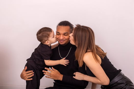 a woman and little boy, kiss a stylish young man on both sides on the cheeks photo