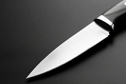 A knife is sitting on top of a black surface photo