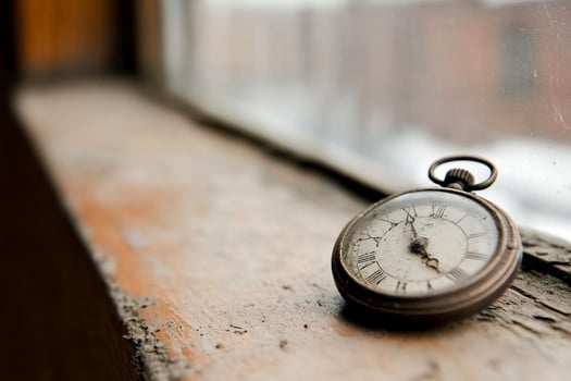An old pocket watch sitting on a window sill photo