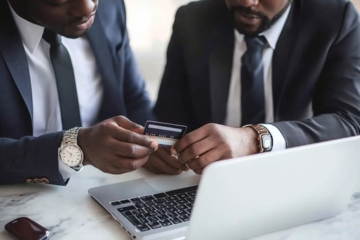 Two men in suits looking at a laptop and credit card photo