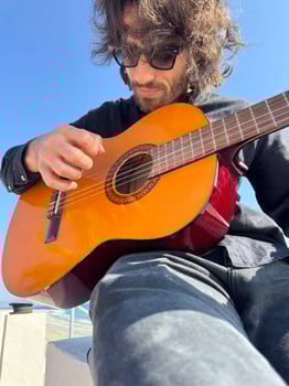 Long Hair Boy Plays Classical Guitar by the Ocean in Summer Dressed Black Outdoor photo