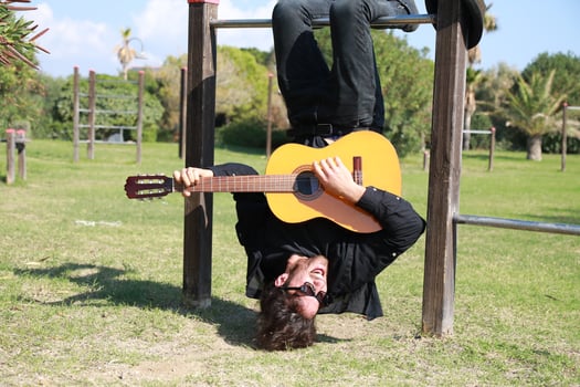 Man Plays Guitar Music Hanging Upside Down In An Outdoor Park photo