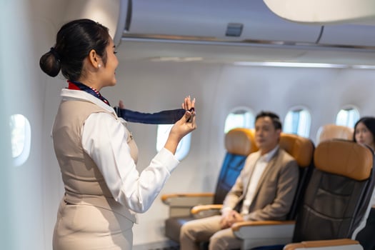 Asian flight attendant is demonstrating safety procedure using seat belt before taking off in the airplane for cabin crew and airline business usage photo