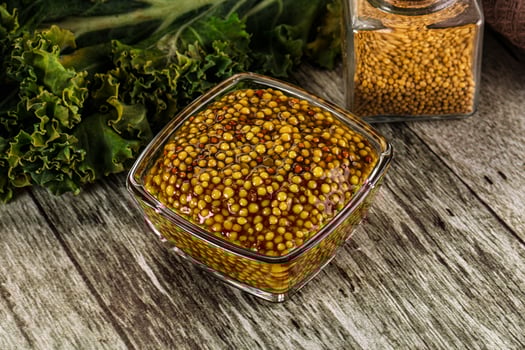 A glass jar with mustard seeds on a wooden table photo