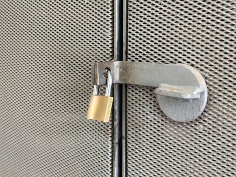 Metal gate with padlock on rusty mesh fence for security and protection photo