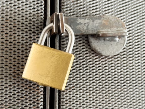 Secure golden padlock on weathered metal mesh door photo