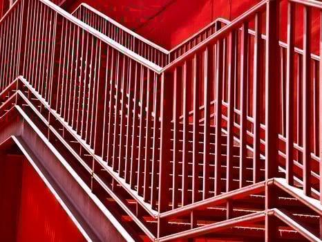 A set of stairs ascending a large red wall photo