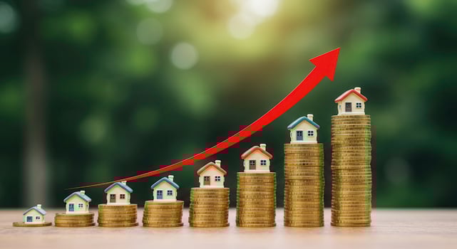 Rising real estate market concept. Miniature houses on stacks of coins with an upward trending arrow, symbolizing property value growth. photo