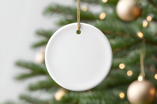 Blank round ornament for mockup hanging on a Christmas tree with golden decorations glowing softly photo