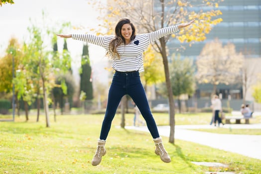 A Joyful Woman is Jumping with Excitement Outdoors in a Beautiful Green Park Setting photo