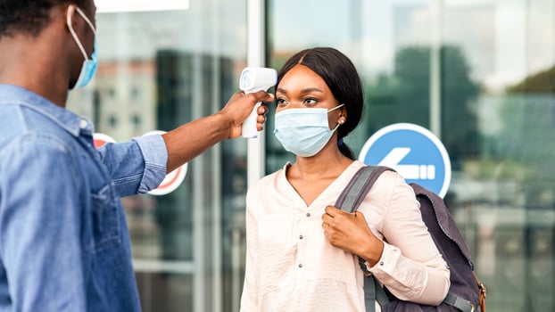 Airport Worker Checking Black Female Passenger's Temperature With Electronic Thermometer After Arrival, Covid-19 Outbreak Prevention photo