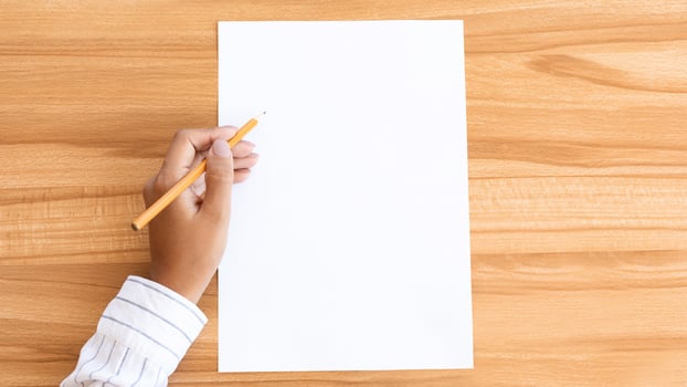 Top view closeup of a lady's hand writing on a piece of paper with a pencil, wooden table background photo