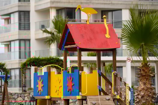 Brightly colored playground structure under a cloudy sky near a coastal setting with vibrant palms in full view photo