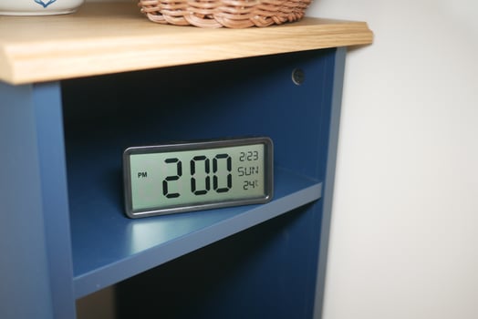 Digital clock displaying time and temperature on a shelf photo