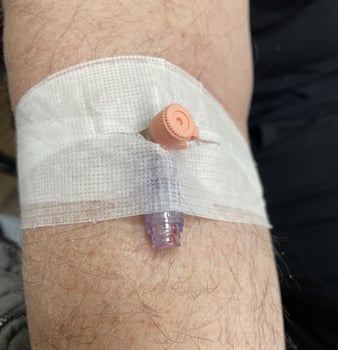Intravenous IV line secured to a persons arm with a white gauze dressing. photo