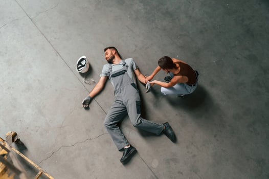 Woman ,hands, checking pulse.. Accident, male factory worker fell, without consciousness, lying down on the floor photo
