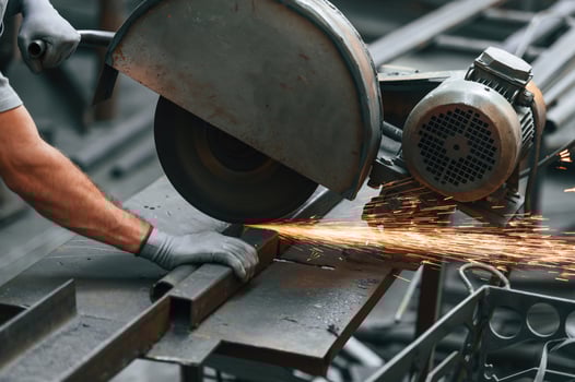 Cutting, the ,metal with a saw. Close up view of man that is working at the factory photo