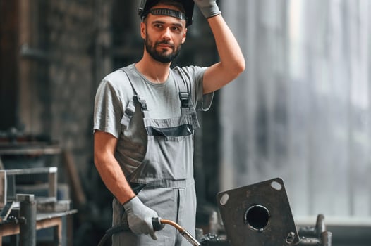 Welder man ,in, safety helmet. Young factory worker in grey uniform photo