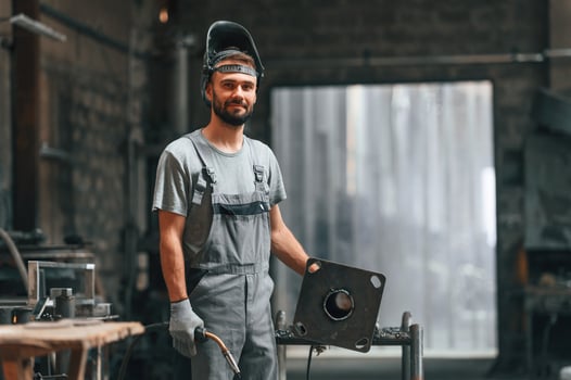 Welder,, man in safety helmet. Young factory worker in grey uniform photo