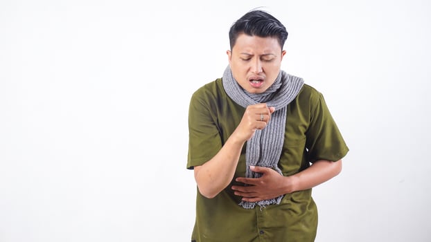 Sick adult man with wool scarf coughing into his fist isolated on white background photo