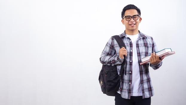 Handsome young Asian male college student with a backpack holding school books standing isolated on white background photo