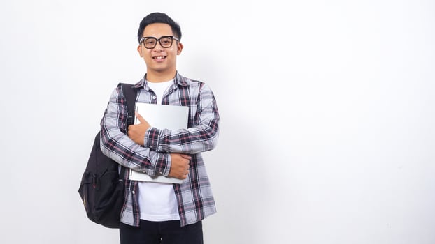 Handsome young Asian male college student with a backpack and holding laptop notebook isolated on white background photo