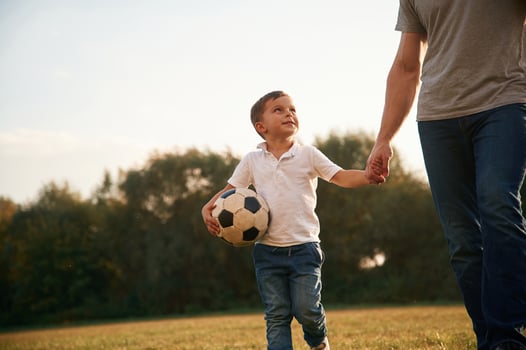 Walking and ,holding ,soccer,ball. Father and little son are playing and having fun outdoors photo