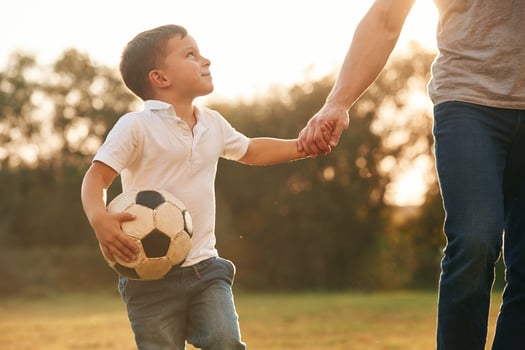 Holding hands and soccer ball. Father and little son are playing and having fun outdoors photo