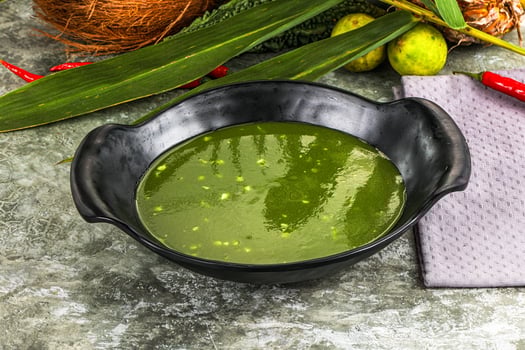 A bowl of green soup with a coconut and some other ingredients photo