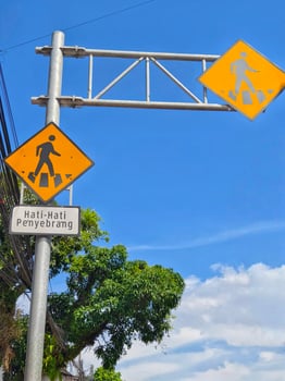 Pedestrian Crossing Road Sign on Metal Pole Against Blue Sky Background photo