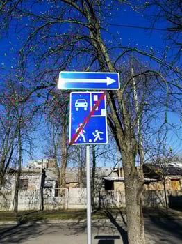 Kyiv, Ukraine - April 11, 2025 Street photo of blue traffic sign indicating end of residential zone. Taken on clear sunny day with trees and houses in background. End of residential zone road sign