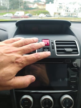 Closeup of a hand reaching for a cars hazard lights button. Illustrates roadside assistance, emergency situations, or car safety. Perfect for automotive, insurance, or travel websites. photo