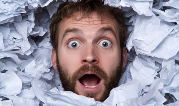 A man is looking surprised in a pile of paper photo