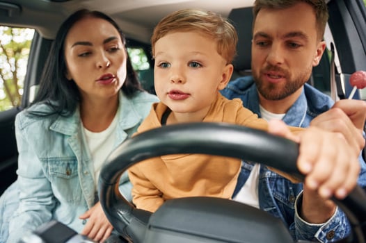 Boy is trying to ride. Family of father, mother and little son ,are sitting ,in the modern car photo