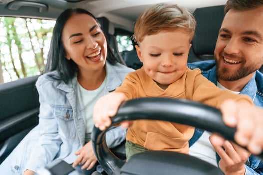 Boy is trying to ride. Family of father, mother and little son are sitting in, the ,modern car photo