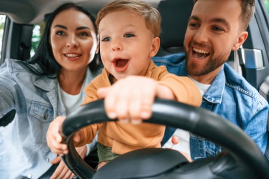 Boy is trying to ride. Family of father, mother and little son are, sitting in the modern ,car photo