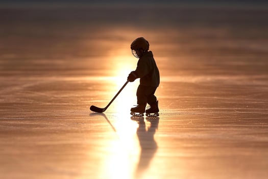 A child playing hockey on an ice rink at sunset photo
