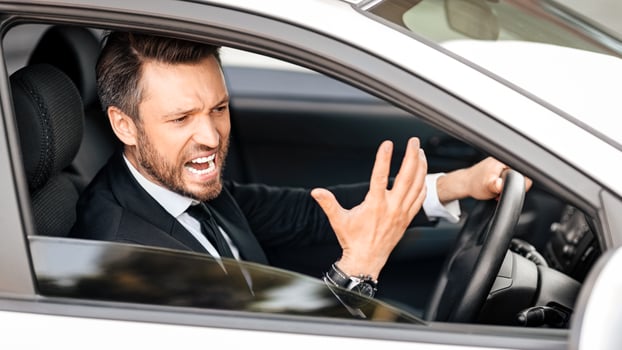 Expressive middle-aged businessman screaming and gesturing while driving car, side view, through window shot. Furious entrepreneur stuck in traffic, getting late for business meeting photo