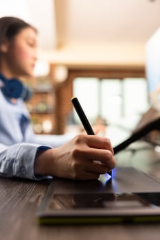 Closeup of asian designer using stylus on digital drawing pad to fine tune and edit photos. Selective focus on individual adjusting color balance with graphic tablet, enhancing images for magazine use photo