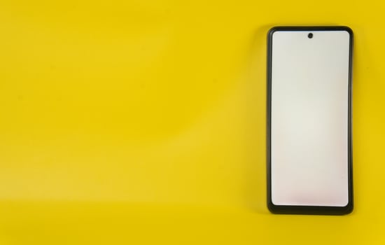 Smartphone with a blank screen against a horizontal yellow background photo