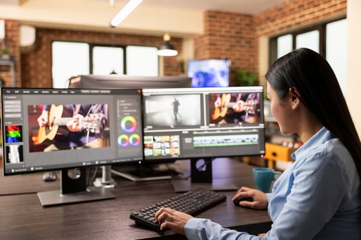 Focused female filmmaker sits at a workstation, carefully refining projects with editing software. Asian woman adjusting clips, processing audio, and enhancing footage with cinematic effects. photo