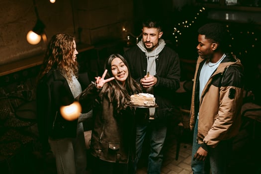Friends celebrating a birthday with cake at a cozy cafe in the evening photo