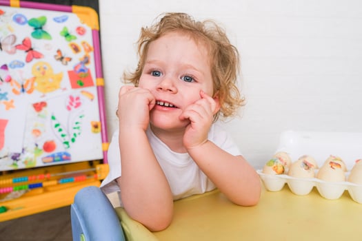 A young child is sitting at a table with a tray of eggs in front of him photo