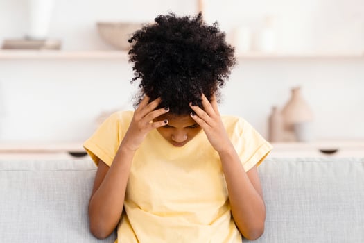 Kid's Headache. Black Teen Girl Touching Head Having Migraine Sitting Unhappy On Sofa Indoors. Copy Space photo