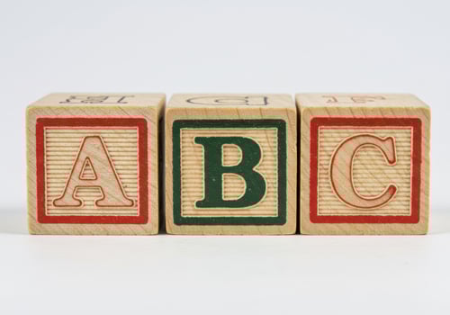 Three wooden blocks spelling the alphabet letters A, B, and C in a row. photo