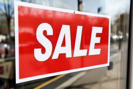 A sale sign hangs in front of a store window photo
