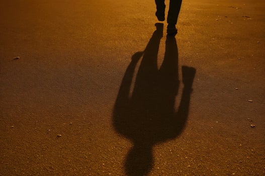 Silhouette shadow of a walking man on sunlit pavement photo