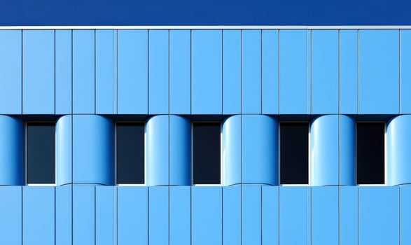 Modern Architectural Design Featuring Blue Facade with Curved Elements and Symmetrical Windows Under Bright Clear Sky photo